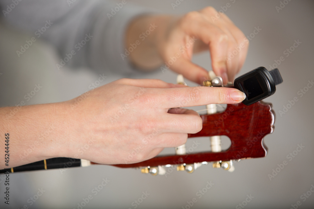 Obraz premium closeup woman musician hands tuning acoustic guitar strings