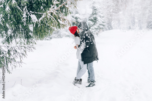 Fototapeta Naklejka Na Ścianę i Meble -  Snow falls from the Christmas tree on the hugging people
