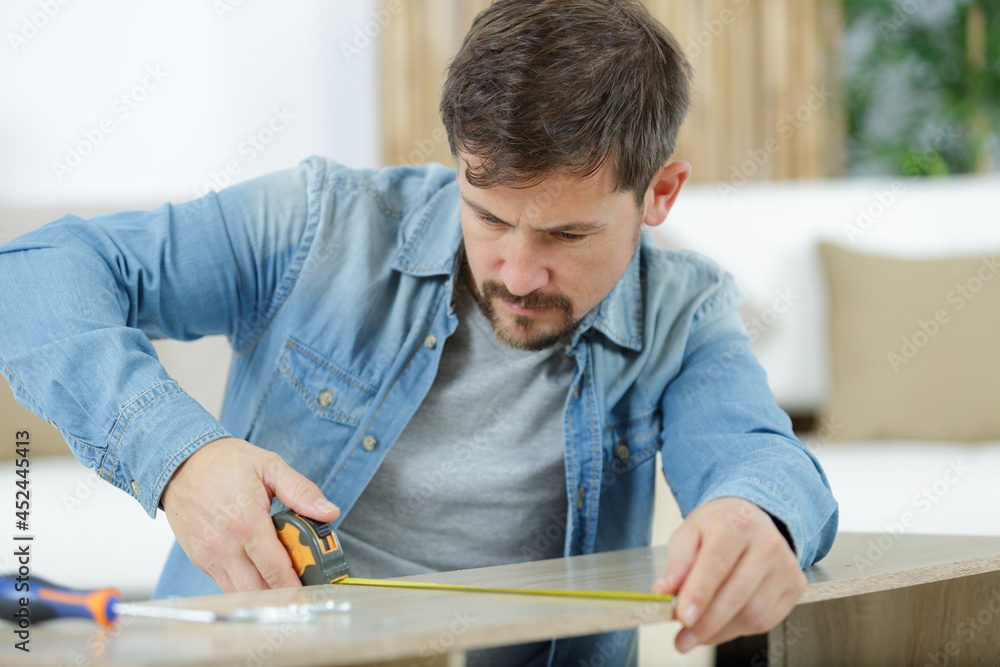 a man worker in the carpenter workroom renovation using tape a man worker in the carpenter workroom renovation using tape