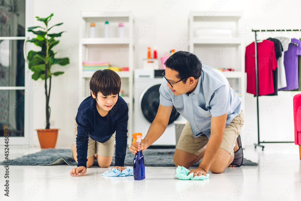 Father teaching asian kid little boy son use disinfectant spray bottle cleaning and washing floor wiping dust with rags while cleaning house together at home Father teaching asian kid little boy son use disinfectant spray bottle cleaning and washing floor wiping dust with rags while cleaning house together at home