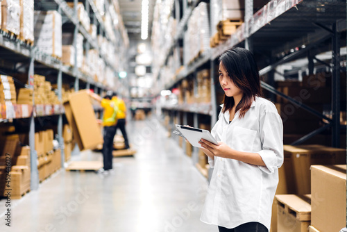 Portrait of asian woman standing and order details on tablet for checking goods and supplies on shelves store at factory with goods background in distribution industry warehouse.logistic and business