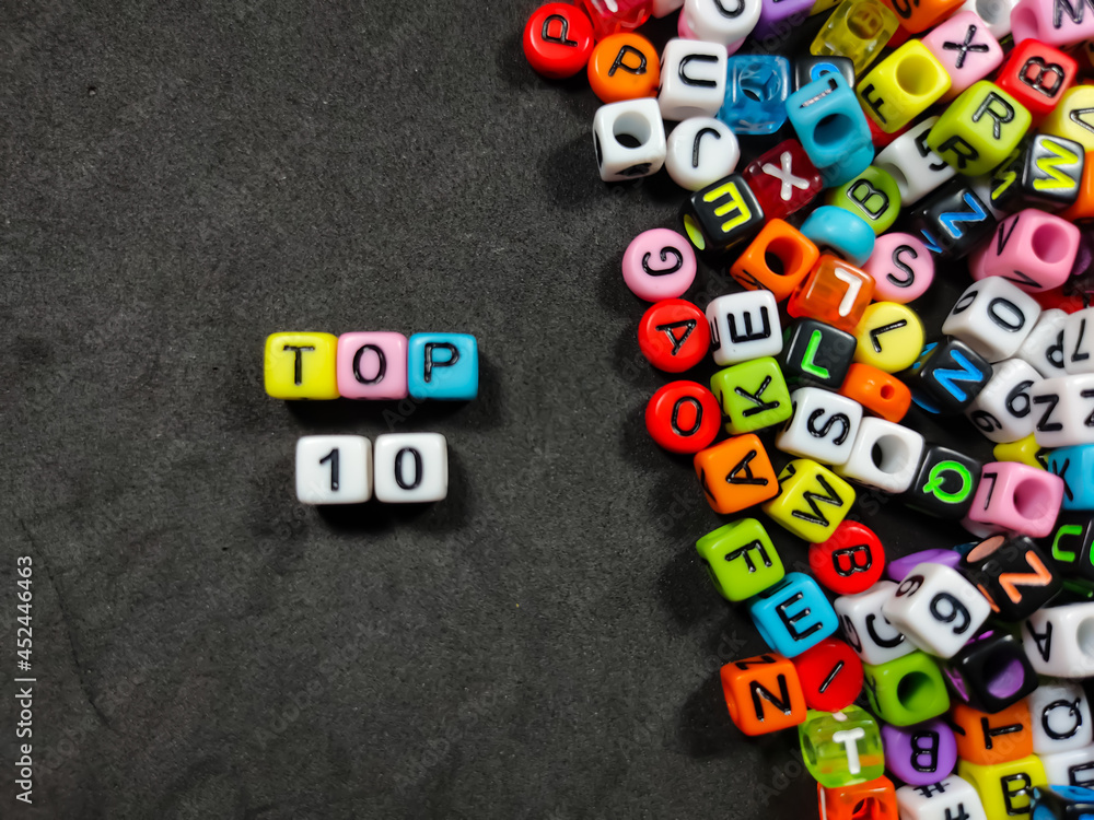 Selective focus.Colorful dice with color letter in word TOP 10 on black background.
