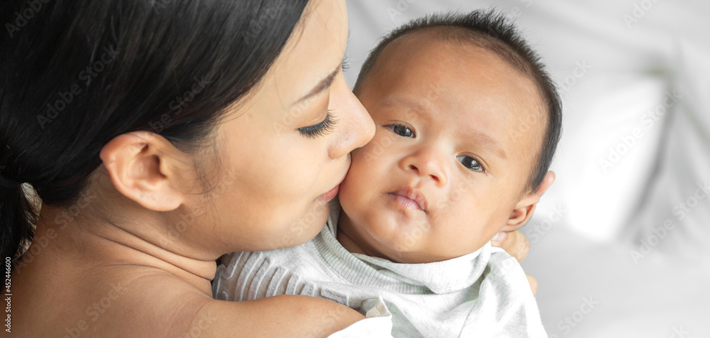 Portrait of enjoy happy love family asian mother playing with adorable little asian baby.Mom touching with cute son moments good time in a white bedroom.Love of family concept Portrait of enjoy happy love family asian mother playing with adorable little asian baby.Mom touching with cute son moments good time in a white bedroom.Love of family concept