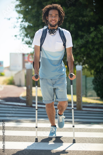 Photography young man on crutches crossing the road