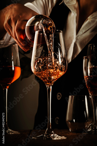 Sommelier pouring rose wine into glass at wine tasting in winery, bar or restaurant. Toned image © 5ph