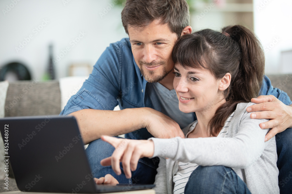 happy couple using a laptop computer in their house happy couple using a laptop computer in their house