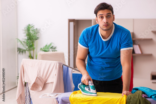 Young man husband doing ironing at home