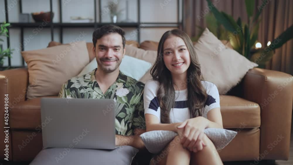 portrait of asian and caucasian marry couple sitting smile relax together on wooden floor in living room at home,marry couple using laptop shopping online together at home portrait of asian and caucasian marry couple sitting smile relax together on wooden floor in living room at home,marry couple using laptop shopping online together at home