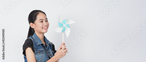 Teenage woman and paper windmill toys. Portrait teen with blue color paper wind wheel wood stick in hand on white background studio shot. Represent wind energy which is pure energy and safe the Earth.