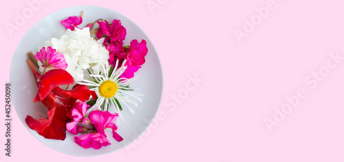 On a white plate, beautiful multi-colored flowers on a pink background.