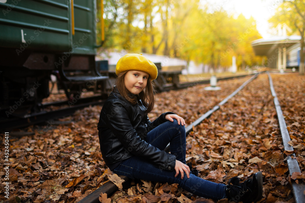 Cute little girl sitting on railway tracks. Crisp autumn day. Cute little girl sitting on railway tracks. Crisp autumn day.