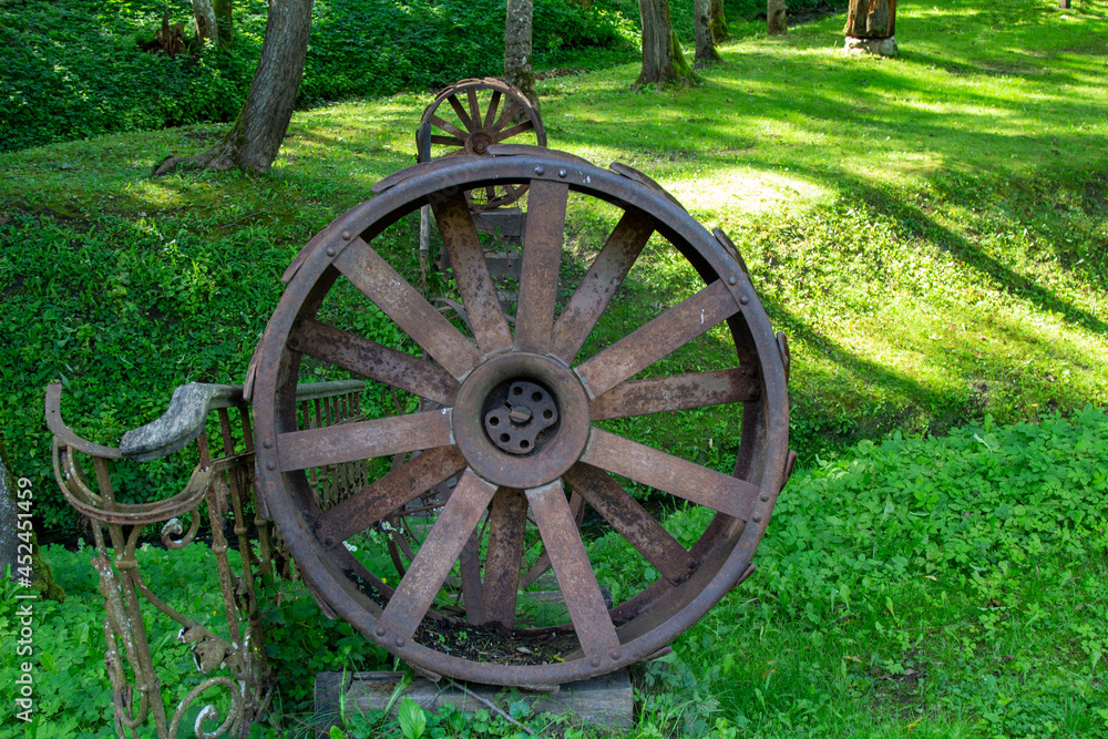 Old parts of mechanisms in the forest. Rusty wheels and parts in the grass
