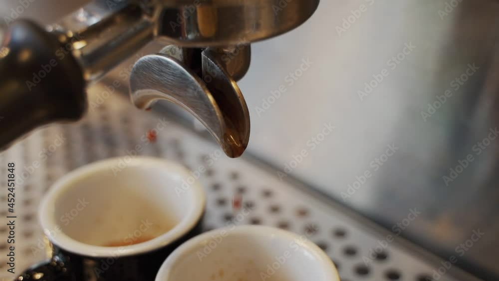 Close up coffee maker machine with black coffee cup. Coffee machine prepares. Coffee espresso preparation. liquid droplet from filter. split share to two cups. Close up coffee maker machine with black coffee cup. Coffee machine prepares. Coffee espresso preparation. liquid droplet from filter. split share to two cups.