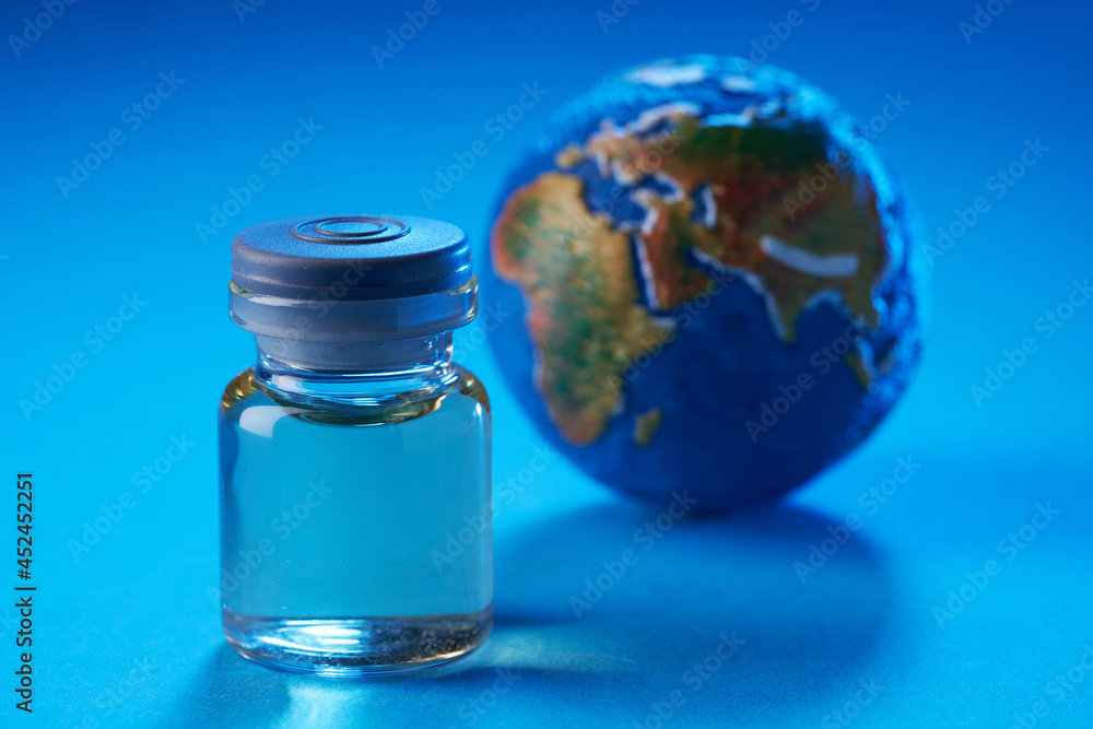 vaccine bottle and globe on blue background vaccine bottle and globe on blue background