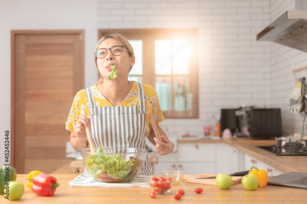 Young woman is eating salad, preparing vegetable salad in modern kitchen Healthy lifestyle concept beautiful woman with mixed vegetable. Young woman is eating salad, preparing vegetable salad in modern kitchen Healthy lifestyle concept beautiful woman with mixed vegetable.