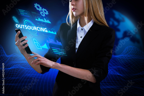 Business, Technology, Internet and network concept. Young businessman working on a virtual screen of the future and sees the inscription: Outsourcing