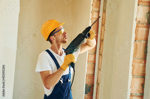 In hard hat. Young man working in uniform at construction at daytime