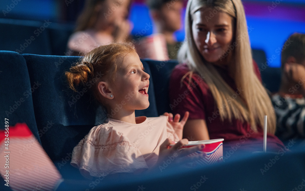 Happy small girl with mother in the cinema, watching film. Happy small girl with mother in the cinema, watching film.