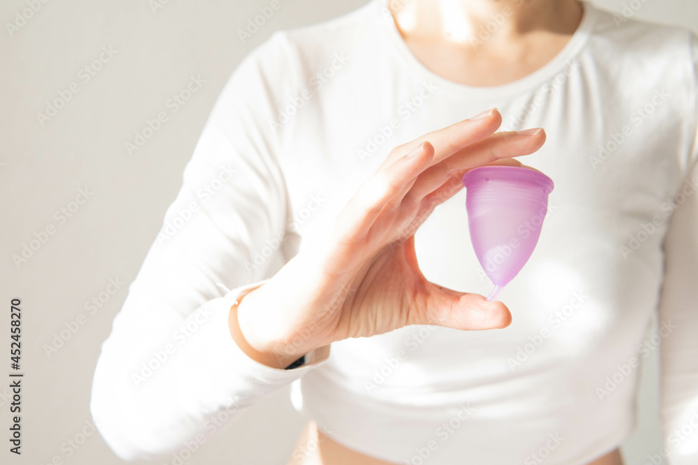 Young woman hand holding menstrual cup with white background