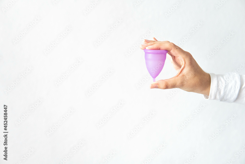 Young woman hand holding menstrual cup with white background