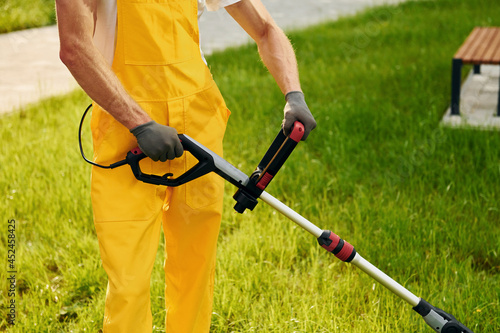 Close up view. Man cut the grass with lawn mover outdoors in the yard