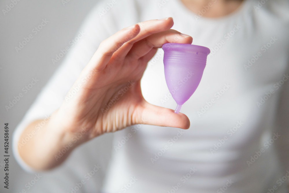 Young woman hand holding menstrual cup with white background