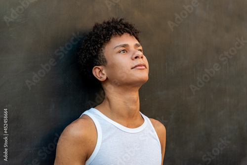 Afro latin male teenager against a wall, looking up. © Viviland