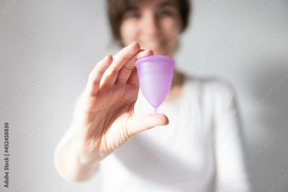 Young woman hand holding menstrual cup with white background