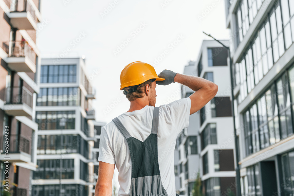 Results of work. Young man in uniform at construction at daytime Results of work. Young man in uniform at construction at daytime