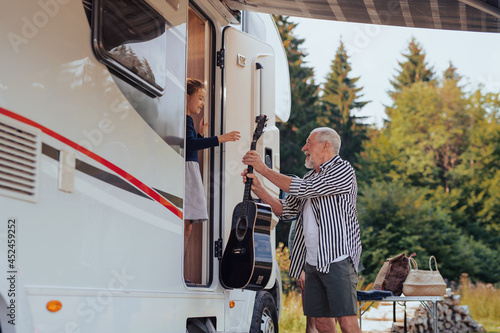 Fotografie Multi-generation family unpacking and talking by car, caravan holiday trip