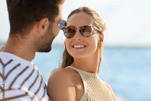 leisure, relationships and people concept - portrait of happy couple on summer beach