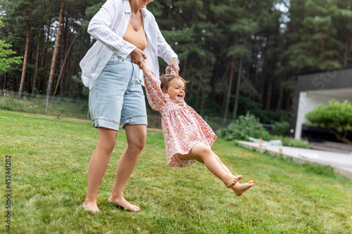 family, motherhood and people concept - happy smiling mother playing with little baby daughter outdoors