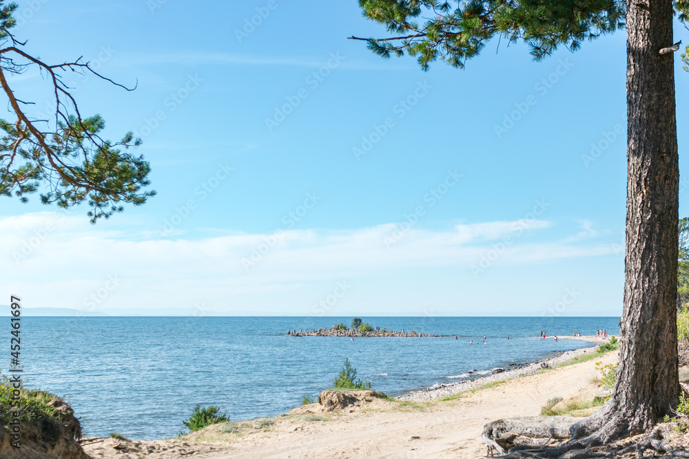Ground back road with pine along calm blue sea coast with little island at summer sunny day, beautiful scenic desert landscape of walking vacation on lake Baikal, shore stroll away