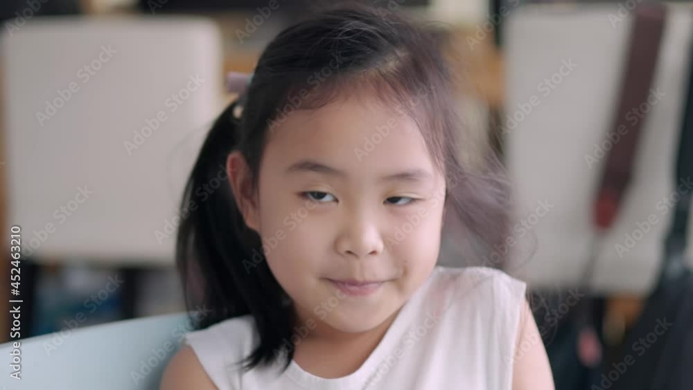 A young Asian girl is happily sitting in the living room looking at the camera. A young Asian girl is happily sitting in the living room looking at the camera.