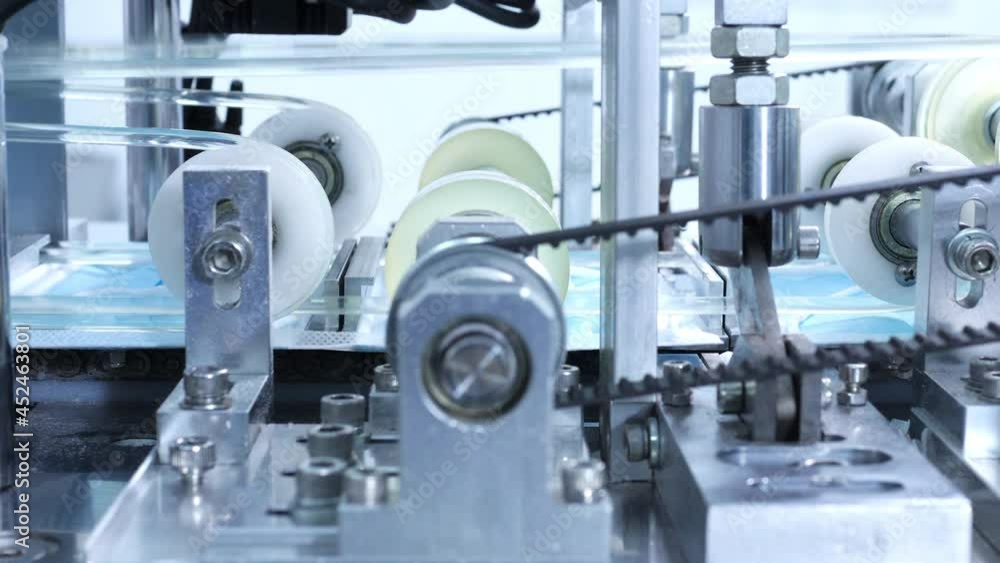 4K Production line of disposable medical face mask working in modern factory. Protective face mask moving on conveyor belt in production machine. Covid-19 pandemic protection and manufacture concept. 4K Production line of disposable medical face mask working in modern factory. Protective face mask moving on conveyor belt in production machine. Covid-19 pandemic protection and manufacture concept.