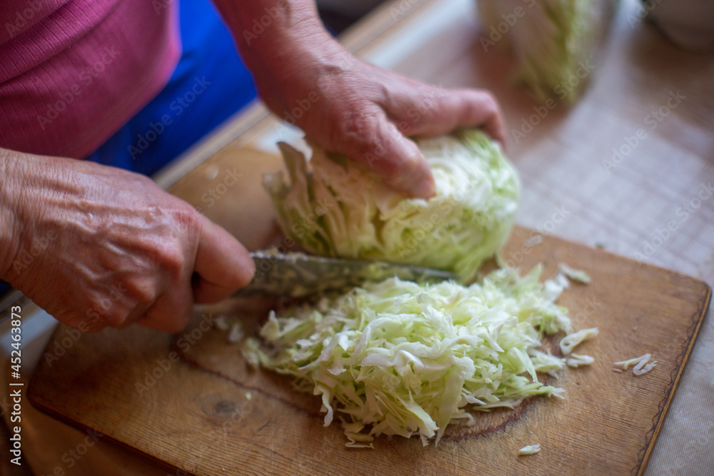 Female hands with a knife chop cabbage for cooking fresh salad Female hands with a knife chop cabbage for cooking fresh salad