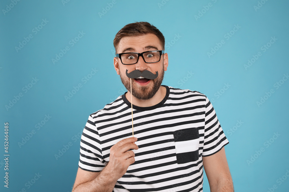 Emotional man with fake mustache on turquoise background Emotional man with fake mustache on turquoise background