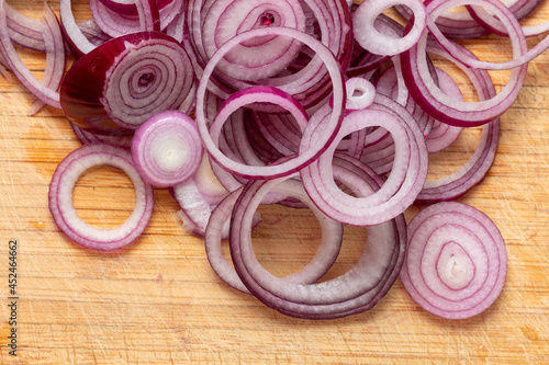 Sliced red onion rings on a wooden board top view close-up