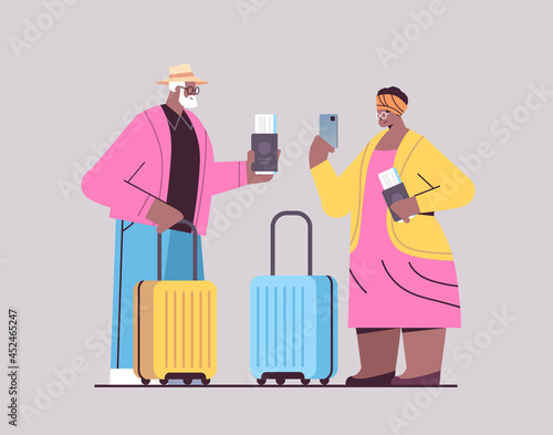 senior couple of tourists using smartphones grandparents with luggage passports and tickets ready to boarding at airport