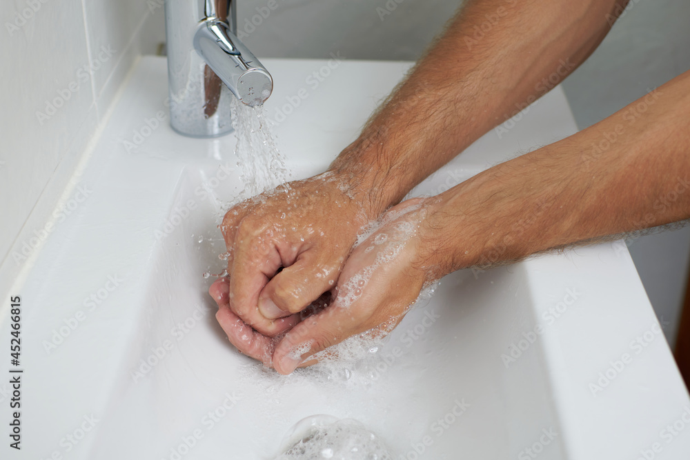 Hand washing with soap in a bathroom with white background Hand washing with soap in a bathroom with white background