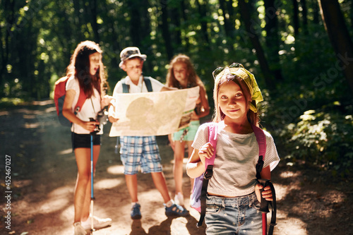 Posing for the camera. Kids strolling in the forest with travel equipment