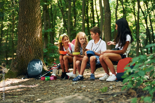 Sitting and having a rest. Kids strolling in the forest with travel equipment © standret