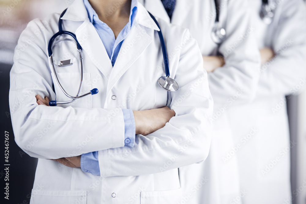 Group of modern doctors standing as a team with arms crossed in sunny hospital and ready to help patients. Medical help, insurance in health care Group of modern doctors standing as a team with arms crossed in sunny hospital and ready to help patients. Medical help, insurance in health care