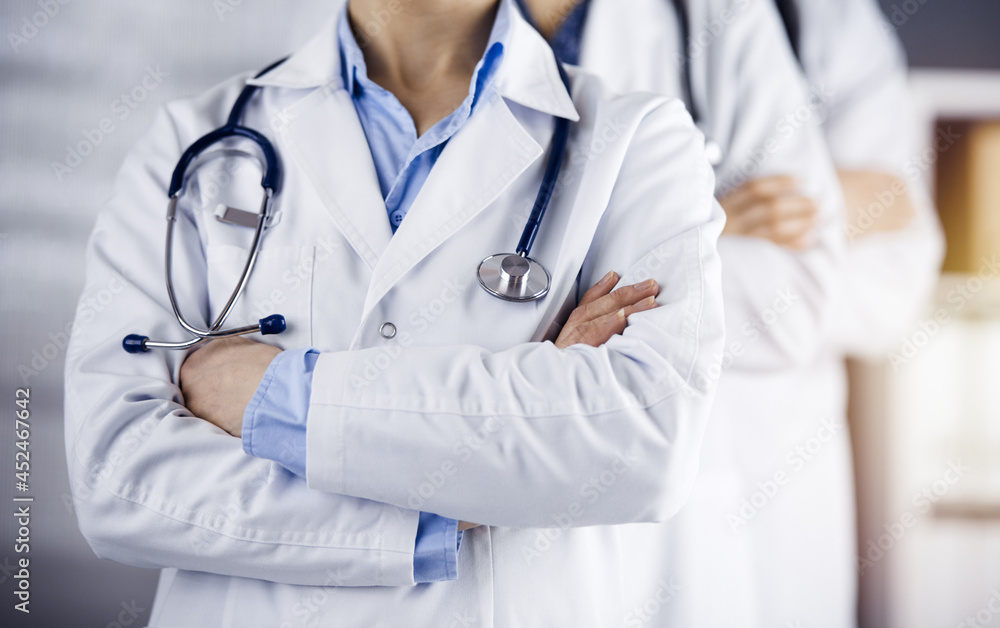 Group of modern doctors standing as a team with arms crossed in sunny hospital and ready to help patients. Medical help, insurance in health care Group of modern doctors standing as a team with arms crossed in sunny hospital and ready to help patients. Medical help, insurance in health care