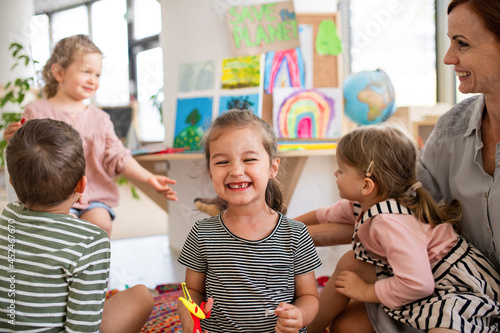 Small girl showing lost baby tooth indoors in classroom, looking at camera.