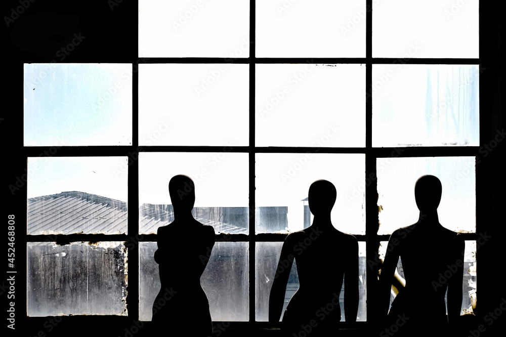 Three mannequins standing in front of a black-framed window.Three mannequins ,Selective focus