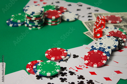 Classic playing cards, chips, red dice and dollars on green background. Gambling and casino concept.