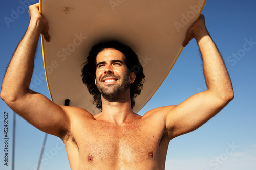 Handsome man with surfboard. Surfer taking a break on the beach..