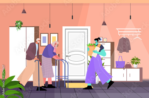 friendly nurse or volunteer bringing food to senior couple home care services healthcare and social support concept
