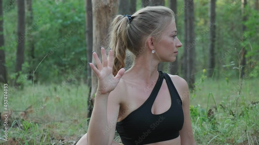 young caucasian woman sitting in wise man pose called marichyasana outdoors at summer forest. fit lady performs yoga exercises, asanas at nature. inner peace, tranquility, bodycare, outdoor stretching young caucasian woman sitting in wise man pose called marichyasana outdoors at summer forest. fit lady performs yoga exercises, asanas at nature. inner peace, tranquility, bodycare, outdoor stretching